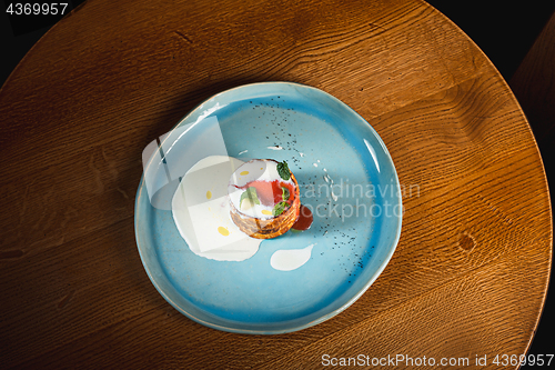 Image of plate with tasty pancakes on wooden table