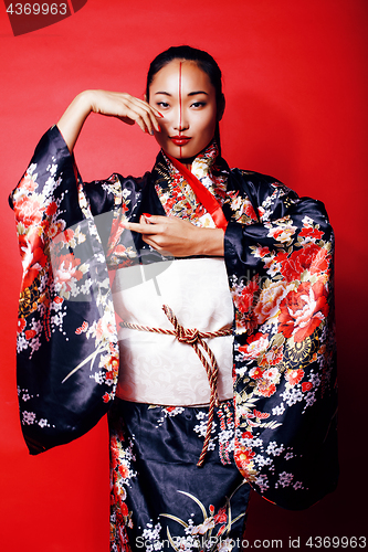 Image of young pretty geisha on red background posing in kimono, oriental people concept close up