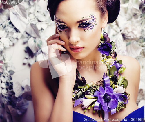 Image of floral face art with anemone in jewelry, sensual young brunette 