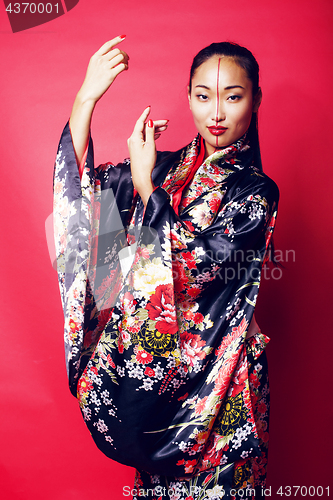 Image of young pretty geisha on red background posing in kimono, oriental people concept close up