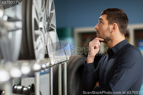 Image of male customer choosing wheel rims at car service