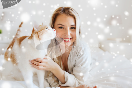 Image of happy young woman with cat in bed at home