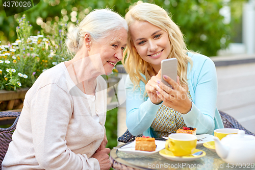 Image of daughter and senior mother with smartphone at cafe