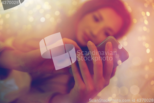 Image of close up of woman with smartphone in bed at home