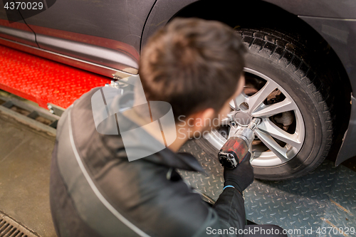 Image of auto mechanic with screwdriver changing car tire