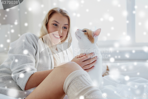 Image of happy young woman with cat in bed at home