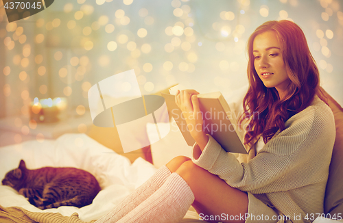 Image of happy young woman reading book in bed at home
