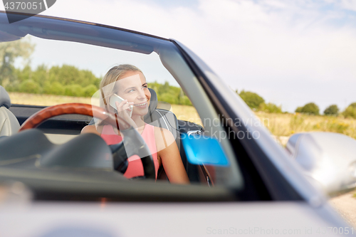 Image of woman calling on smartphone at convertible car