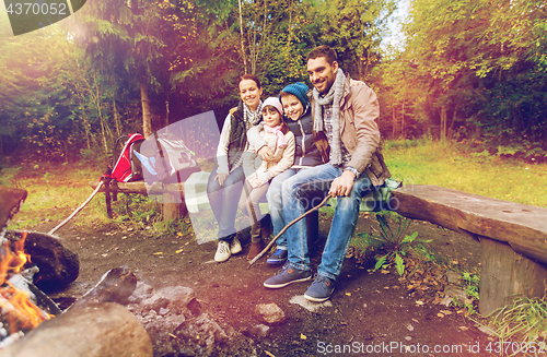 Image of happy family sitting on bench at camp fire