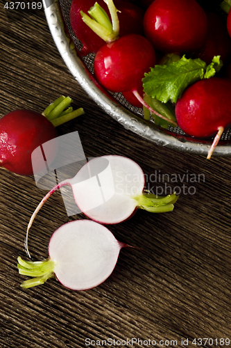 Image of Several red radishes on a wooden board.