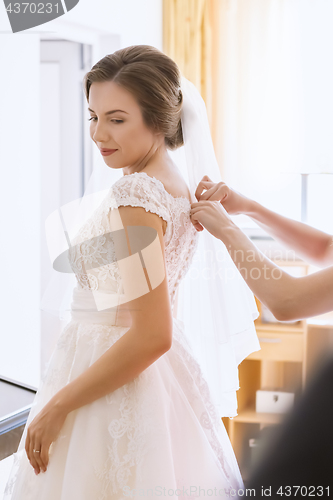 Image of Beautiful young bride in wedding dress in living room