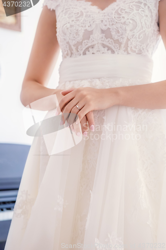 Image of bride’s hand with wedding ring on dress