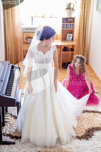 Image of Beautiful young bride in wedding dress in living room