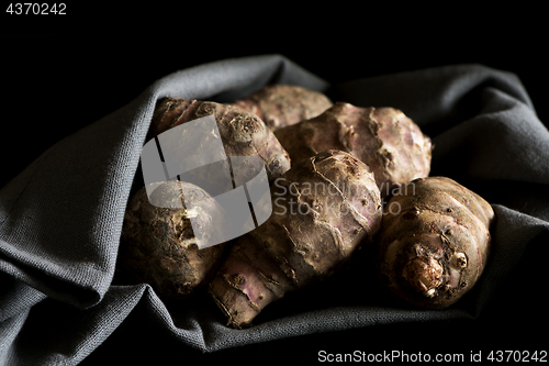 Image of Several Jerusalem artichokes on a gray cotton napkin.