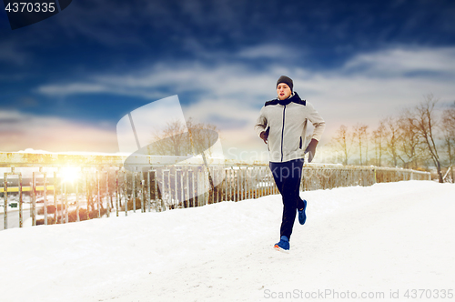 Image of man running along snow covered winter bridge road