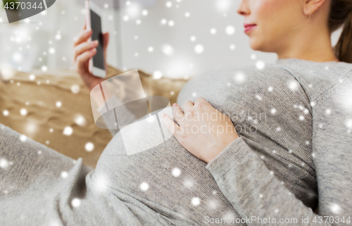 Image of happy pregnant woman with smartphone at home