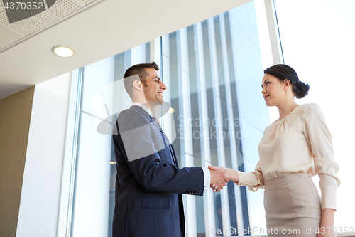 Image of smiling business people shaking hands at office