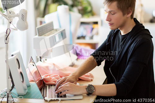 Image of fashion designer with laptop working at studio