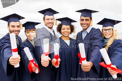 Image of happy students in mortar boards with diplomas