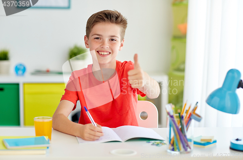 Image of happy student boy writing to notebook at home