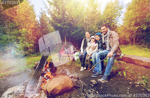 Image of happy family sitting on bench at camp fire