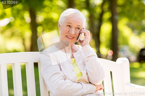 Image of happy senior woman calling on smartphone in summer