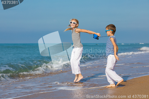 Image of Two happy children playing on the beach at the day time