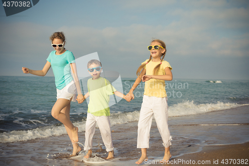 Image of Three happy children running on the beach at the day time.