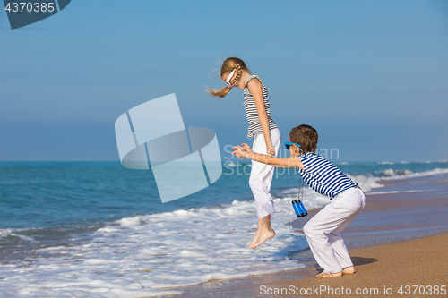 Image of Two happy children playing on the beach at the day time