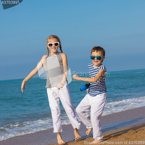 Image of Two happy children playing on the beach at the day time