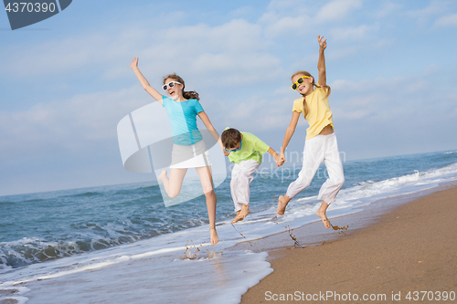 Image of Three happy children running on the beach at the day time.