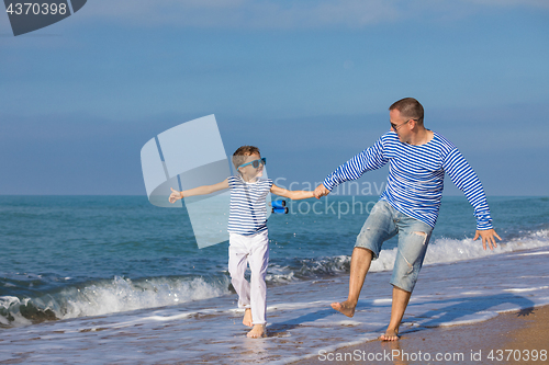 Image of Father and son playing on the beach at the day time. Concept of 