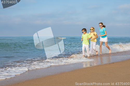 Image of Three happy children running on the beach at the day time.