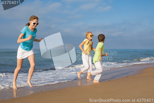 Image of Three happy children running on the beach at the day time.