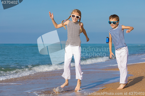 Image of Two happy children playing on the beach at the day time