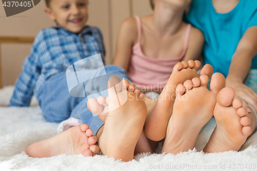 Image of Happy brother and sisters  sitting on the bed barefoot