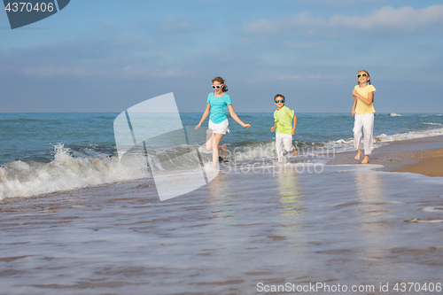 Image of Three happy children running on the beach at the day time.