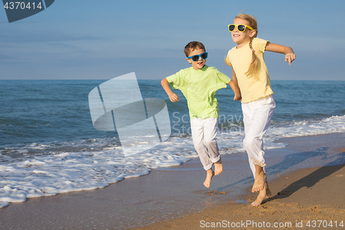 Image of Two happy children playing on the beach at the day time