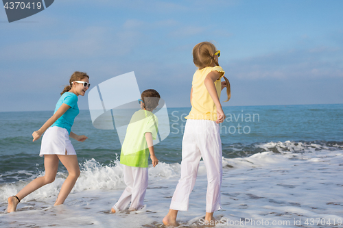 Image of Three happy children running on the beach at the day time.