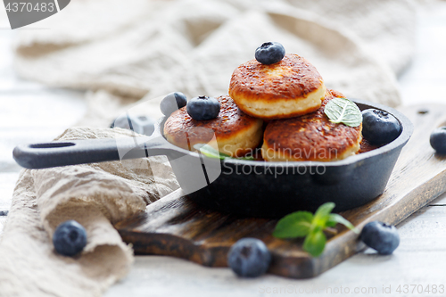 Image of Cheese pancakes and blueberries in cast iron pan.