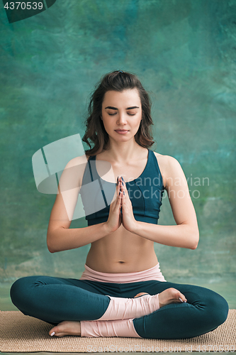 Image of Studio shot of a young woman doing yoga exercises on green background