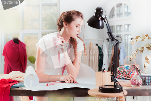 Image of Fashion designers working in studio sitting on the desk