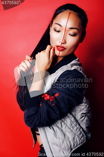 Image of young pretty asian girl posing cheerful on red background, fashion style makeup and hair, lifestyle modern orient people concept