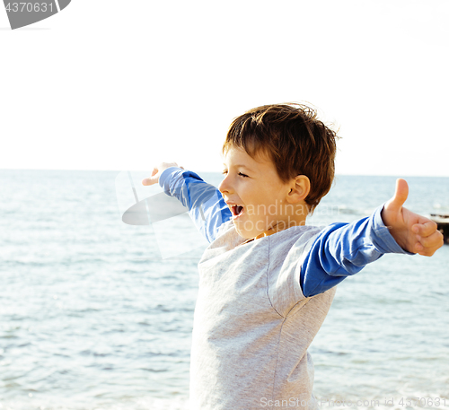 Image of little cute boy on sea coast thumbs up