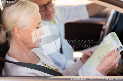 Image of happy senior couple with map driving in car