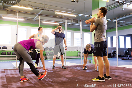 Image of group of happy friends stretching in gym