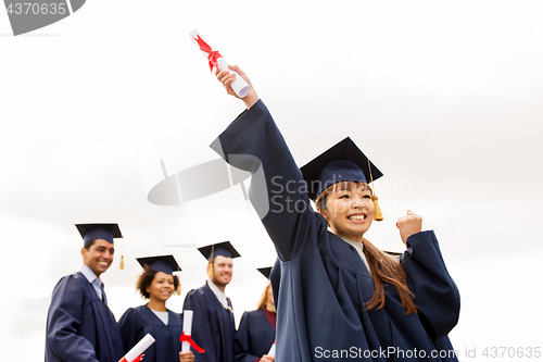 Image of happy students in mortar boards with diplomas