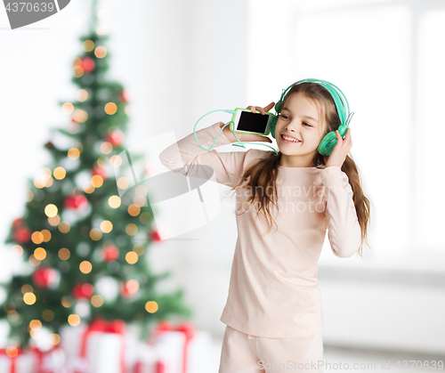 Image of girl with smartphone and headphones at christmas
