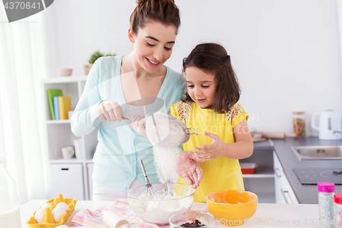 Image of happy mother and daughter baking at home