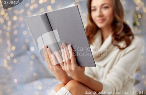 Image of happy young woman reading book in bed at home